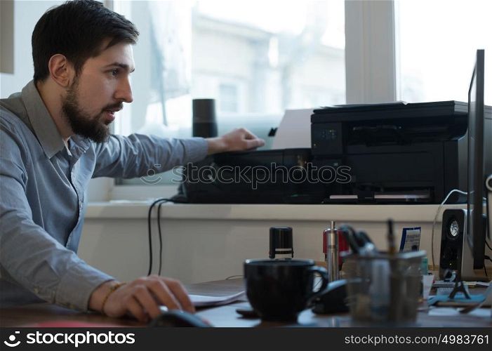 Handsome businessman scanning and printing document in office