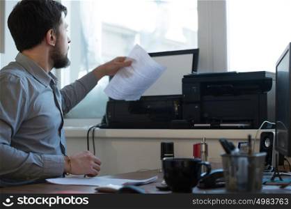 Handsome businessman scanning and printing document in office