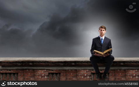 Handsome businessman sitting on top and reading book