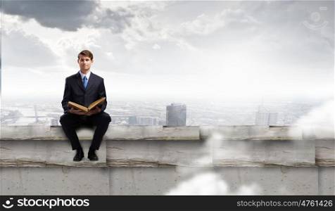 Handsome businessman sitting on top and reading book