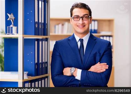 Handsome businessman standing next to shelf