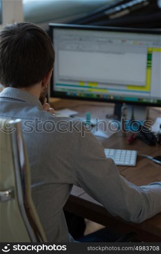 Handsome businessman working with computer in office. Photo from behind