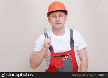 Handsome car mechanic male worker holding equipment tool, wrench standing in red uniform, safety helmet on white background. labor day.. Handsome car mechanic male worker holding equipment tool, wrench standing in red uniform, safety helmet on white background. labor day