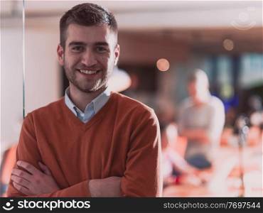 Handsome casual businessman standing confident in the office. Disabled businesswoman in wheelchair working together with the team in the background. High quality photo. Follow focus. . Handsome young business man standing confident in the office in front of his team