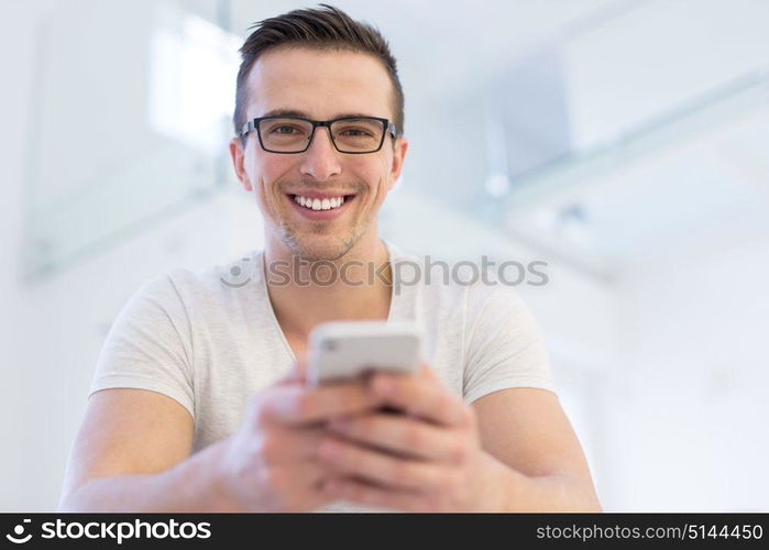 Handsome casual young man using a mobile phone at home