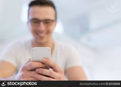 Handsome casual young man using a mobile phone at home