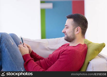 Handsome casual young man using a mobile phone at home