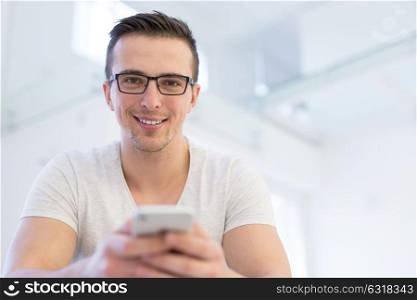 Handsome casual young man using a mobile phone at home