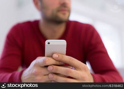 Handsome casual young man using a mobile phone at home