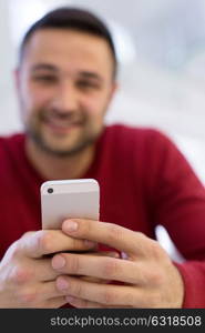 Handsome casual young man using a mobile phone at home