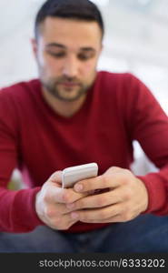 Handsome casual young man using a mobile phone at home