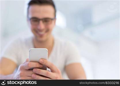 Handsome casual young man using a mobile phone at home