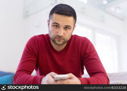 Handsome casual young man using a mobile phone at home