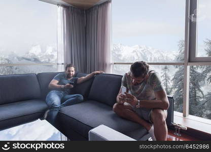 Handsome casual young men using a mobile phones near the window at home