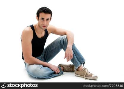 Handsome Caucasian guy wearing black tank top and jeans sitting on floor, isolated