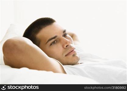 Handsome Caucasian mid adult man lying with hands behind head.