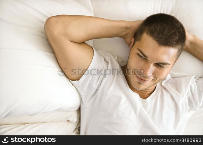 Handsome Caucasian mid adult man lying with hands behind head smiling.