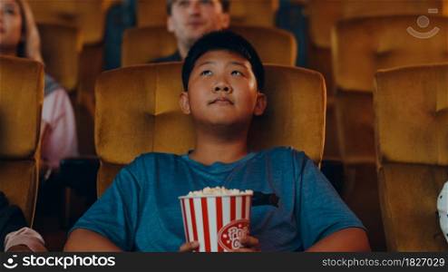 Handsome cheerful young asian boy laughing while watching film in movie theater. Lifestyle entertainment concept.