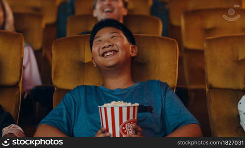 Handsome cheerful young asian boy laughing while watching film in movie theater. Lifestyle entertainment concept.