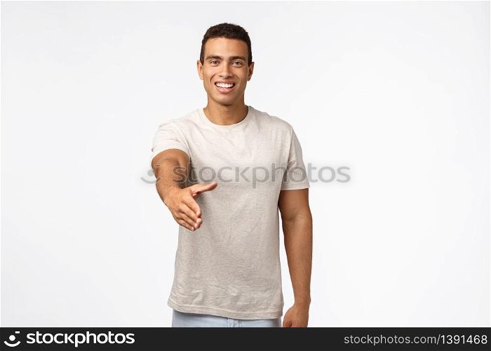 Handsome confident and friendly young masculine man in t-shirt, stretch hand forward for handshake, smiling say nice to meet you, greeting hi or hello someone, standing white background cheerful.. Handsome confident and friendly young masculine man in t-shirt, stretch hand forward for handshake, smiling say nice to meet you, greeting hi or hello someone, standing white background cheerful
