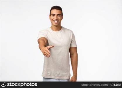 Handsome confident and friendly young masculine man in t-shirt, stretch hand forward for handshake, smiling say nice to meet you, greeting hi or hello someone, standing white background cheerful.. Handsome confident and friendly young masculine man in t-shirt, stretch hand forward for handshake, smiling say nice to meet you, greeting hi or hello someone, standing white background cheerful