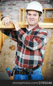 Handsome construction worker carrying lumber on his shoulder. Authentic accurate picture in accordance with safety and code regulations.