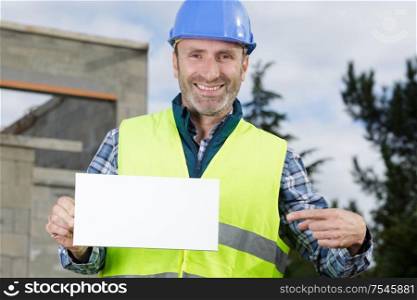 handsome construction worker showing a sign