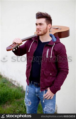 Handsome cool man carrying a guitar on his shoulders