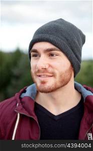 Handsome cool man with cap wool smiling outside