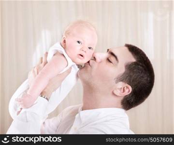 Handsome daddy kissing cute little toddler, man enjoying time spend with his little newborn daughter at home, love concept