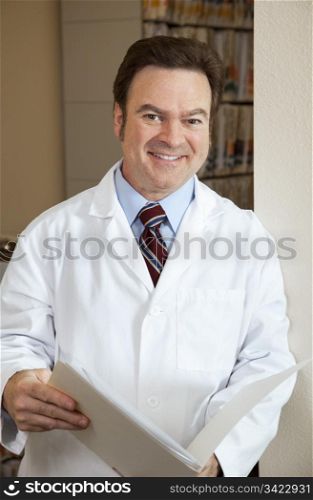 Handsome doctor in his filing room reviewing a chart.