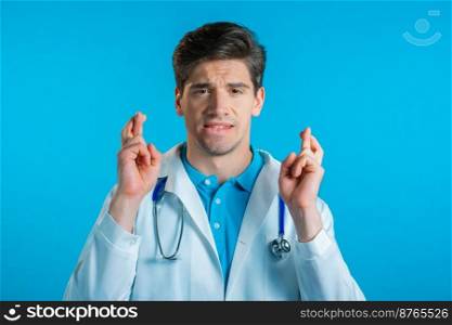 Handsome doctor praying over blue background. Man begging someone satisfy his desires, help with. High quality photo. Handsome doctor praying over blue background. Man begging someone satisfy his desires, help with.