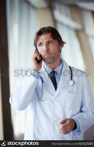 handsome doctor speaking on cellphone at modern hospital indoors