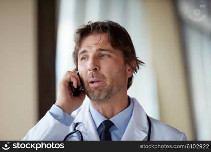 handsome doctor speaking on cellphone at modern hospital indoors