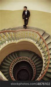 Handsome elegant man standing on the old fashioned stairs
