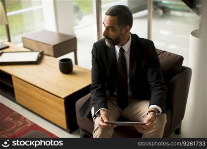 Handsome elegant mature business man using multitasking multimedia digital tablet in the office
