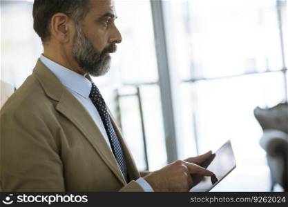 Handsome elegant mature business man using multitasking multimedia digital tablet in the office