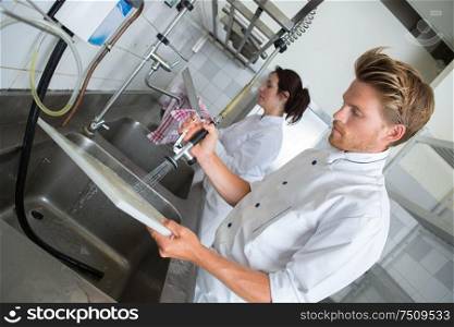 handsome employee doing dishes in commercial kitchen