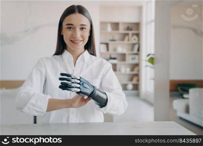 Handsome european girl has high tech carbon electronic hand. Disabled young woman is assembling bionic arm with hand. Girl is setting the prosthesis functions. Modern technology for wellbeing.. Handsome european girl has high tech carbon electronic hand. Modern technology for wellbeing.