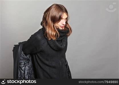 Handsome fashion man getting dressed.. Handsome fashionable man getting dressed wearing black coat and scarf. Young guy posing in studio. Winter or autumn fashion.