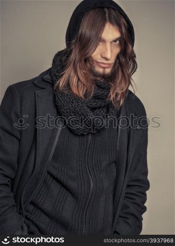 Handsome fashion man portrait wearing black coat.. Portrait of handsome fashionable man wearing black coat and scarf. Young guy posing in studio. Winter or autumn fashion. Instagram filter.