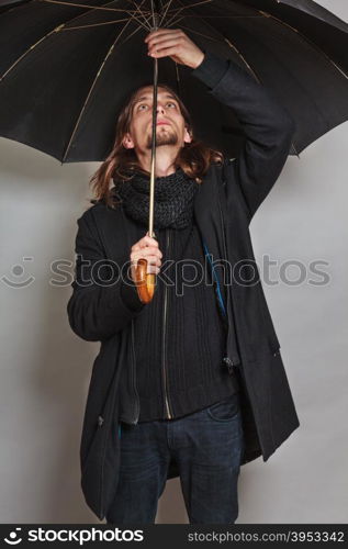 Handsome fashion man portrait wearing black coat.. Portrait of handsome fashionable man wearing black coat and scarf holding umbrella. Young guy posing in studio. Winter or autumn fashion.