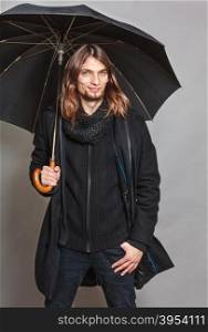 Handsome fashion man portrait wearing black coat.. Portrait of handsome fashionable man wearing black coat and scarf holding umbrella. Young guy posing in studio. Winter or autumn fashion.