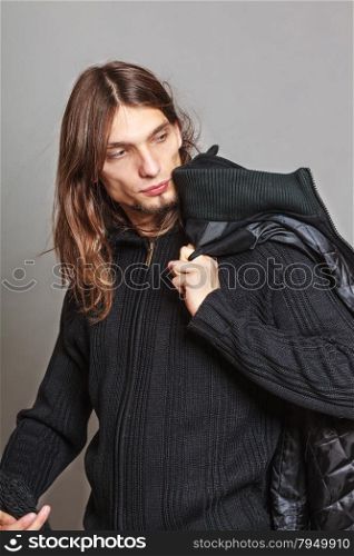 Handsome fashion man portrait wearing black coat.. Portrait of handsome fashionable man wearing black sweater and scarf holding coat. Young guy posing in studio. Winter or autumn fashion.