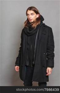 Handsome fashion man portrait wearing black coat.. Portrait of handsome fashionable man wearing black coat and scarf. Young guy posing in studio. Winter or autumn fashion.