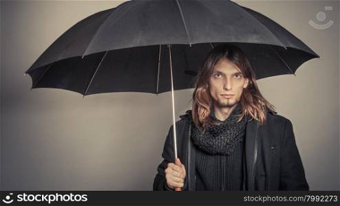 Handsome fashion man portrait wearing black coat.. Portrait of handsome fashionable man wearing black coat and scarf holding umbrella. Young guy posing in studio. Winter or autumn fashion. Instagram filter.