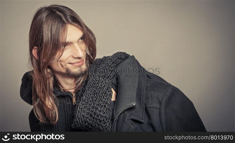 Handsome fashion man portrait wearing black coat.. Portrait of handsome fashionable man wearing black sweater and scarf holding coat. Young guy posing in studio. Winter or autumn fashion. Instagram filter.