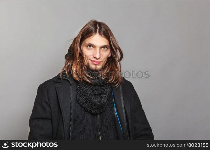 Handsome fashion man portrait wearing black coat.. Portrait of handsome fashionable man wearing black coat and scarf. Young guy posing in studio. Winter or autumn fashion.