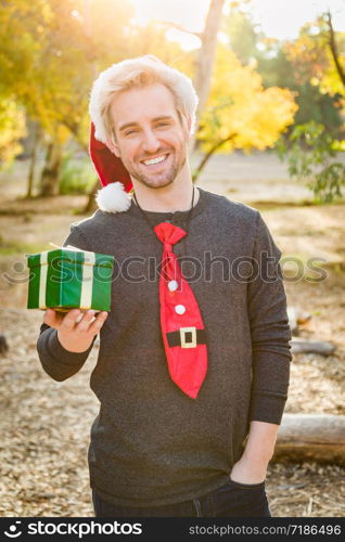 Handsome Festive Young Caucasian Man Holding Christmas Gift Outdoors.