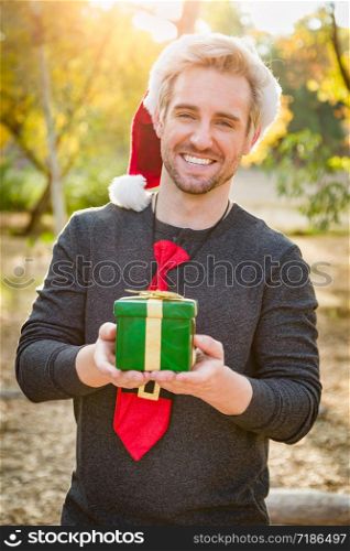 Handsome Festive Young Caucasian Man Holding Christmas Gift Outdoors.